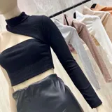 Top corto negro de tejido de punto acanalado, con cuello alto y manga larga en un solo brazo.