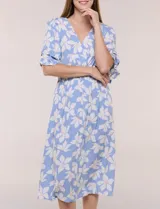 Vestido midi de calce holgado y caída fluida con escote en V cruzado, cintura elastizada fruncida y mangas cortas con volados superpuestos. Cuenta con un diseño estampado de flores grandes en tonos amarillo, blanco, azul marino y verde.