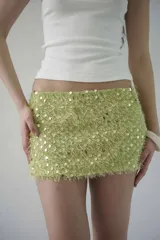 Minifalda de tiro bajo confeccionada en tejido texturizado color verde lima, con apliques de lentejuelas circulares brillantes.