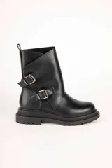 Bota de caña media color negro, de estilo biker, con suela chunky y dos tiras con hebillas metálicas en el lateral.