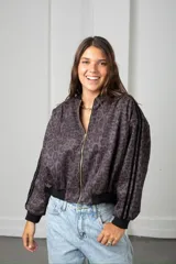 Campera tipo bomber de gamuza con estampado animal print en tonos bordó y negro. Presenta cierre frontal dorado, puños y cintura elástica en color negro, y detalle de franjas laterales en las mangas.