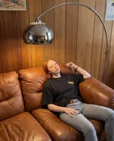 Remera negra de corte oversize con estampado gráfico en la espalda que incluye ilustraciones de carpinchos sobre una cuadrícula y texto descriptivo en color blanco y naranja.