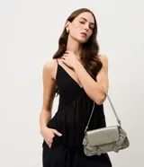 Cartera modelo baguette de tamaño pequeño, con formato estructurado, tapa delantera y detalles de hebillas decorativas. Cuenta con asa para hombro e interior forrado con compartimento.