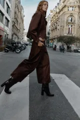 Pantalón culotte marrón de tiro alto con efecto ante, bolsillos delanteros y traseros, pernera ancha y corta. El bajo está troquelado con un diseño floral. Cierre frontal con cremallera y botón.