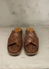 Sandalias de cuero color marrón con diseño cruzado y suela plana.