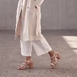 Sandalias de cuero color marrón, con taco ancho, diseño de tiras cruzadas y hebilla metálica de ajuste en el tobillo.