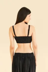 Top negro con volantes y pespuntes brillantes, escote cuadrado delante y detrás, tirantes con ajustadores y detalle de solapa en capas en el busto.