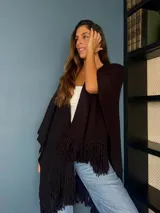 Ruana tejida a mano en punto arroz con lana merino, presenta un diseño envolvente con flecos en los extremos.