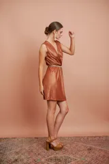 Vestido corto de jersey metalizado color cobre, sin mangas, con escote en V cruzado y falda recta.