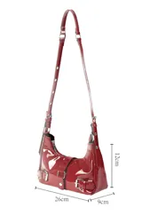 Bandolera de charol color rojo, con diseño estilo baguette. Presenta cierre superior, correas ajustables con hebillas metálicas y detalles decorativos de hebillas en la parte frontal.