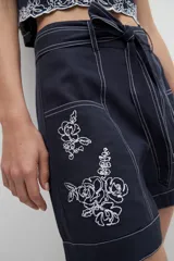 Short azul marino con bordado floral blanco, tiro alto y cinturón de lazo.