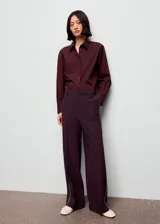 Pantalon de corte recto en color morado oscuro, con tiro medio y detalle de ribete (piping) en contraste a lo largo de las piernas. Cuenta con bolsillos laterales, cierre oculto y trabillas para cinturón.