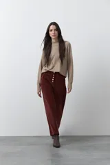 Pantalón de pana color bordó, de corte wide leg y tiro alto. Presenta cierre frontal con botones dorados visibles, bolsillos laterales con detalles bordados y silueta amplia.