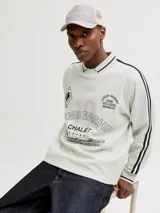 Buzo de manga larga color gris melange, con cuello tipo polo y ajuste holgado. Presenta estampado gráfico frontal con tipografía y detalles en negro, además de bandas laterales en las mangas.