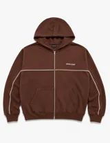 Campera con capucha de corte boxy color marrón, con cierre frontal completo y bolsillos tipo canguro. Presenta una línea blanca horizontal en el pecho que se extiende por las mangas y un pequeño bordado con texto en el pecho.