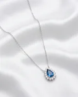 Collar de plata 925 con cadena fina y dije en forma de lágrima, con un cristal central azul zafiro rodeado por pequeñas circonias brillantes.