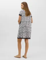 Camisón corto de tejido soft, color blanco con estampado floral y de hojas en tonos azules y marrones. Cuenta con mangas cortas y escote en V con terminaciones de encaje azul en el cuello, las mangas y el ruedo.