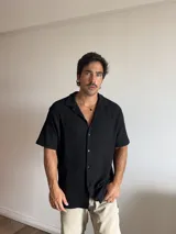 Camisa negra de manga corta, con cuello tipo solapa y textura de punto.