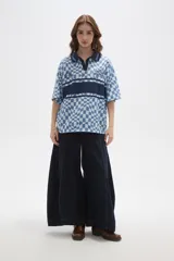 Remera tipo chomba de manga corta con cuello camisero, confeccionada en tejido con estampado de tablero ondulado en tonos rosado y blanco, con franja horizontal y detalles gráficos en color bordó.