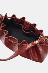 Mini bolso de hombro en color bordó con textura efecto reptil, diseño fruncido con cordones ajustables en los laterales y una sola asa superior.