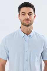 Camisa de manga corta confeccionada en mezcla de lino y algodón, color beige, con cuello camisero abotonado, bolsillo frontal en el pecho y cierre de botones.