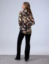 Camisa de gasa negra con estampado de flores en tonos marrones y beige. Tiene cuello con solapa, abertura central con botones y mangas 3/4 con puño fruncido.