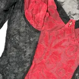 Body de encaje negro con paneles centrales en color bordó, mangas largas acampanadas y detalle de pequeña cruz metálica en el busto.