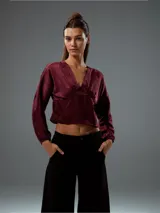 Top corto color bordó, con escote en V, mangas largas abullonadas con puños elásticos y fruncido en la parte delantera.