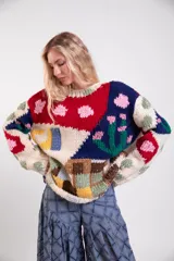 Sweater tejido a mano de lana merino, de diseño holgado con cuello redondo y mangas largas, con un colorido patrón de intarsias que representa escenas de paisajes con casas, cactus y flores.