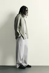Pantalón jogger de corte relajado y pernera ancha, confeccionado en tejido de algodón con interior perchado. Cuenta con cintura elástica ajustable mediante cordón interior, bolsillos laterales y un bolsillo trasero de plastrón.