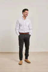 Pantalón de vestir verde oliva, de corte slim fit, sin pinzas, con bolsillos laterales y traseros. Se ajusta a la cintura con cinturón de cuero marrón.