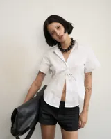 Camisa blanca de poplin, corte al cuerpo, con cuello clásico y cierre frontal con botones.