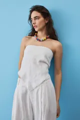 Blusa strapless azul marino de corte asimétrico con terminación en punta y flecos sutiles en el borde inferior, diseño de escote palabra de honor.