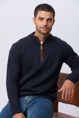 Buzo tejido de punto grueso en color azul marino, con cuello alto y cierre frontal parcial. Presenta detalles en gamuza en la zona del cierre y una textura en relieve en toda la prenda.