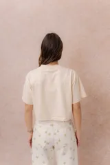 Remera crop color beige, de calce amplio, escote redondo y mangas cortas sueltas.