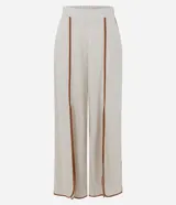 Pantalón largo tipo palazzo de color beige, confeccionado en mezcla de viscosa y lino. Presenta tiro alto, cintura elastizada en la parte posterior y aberturas frontales en las piernas con ribetes en tono marrón contrastante.