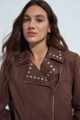 Campera estilo biker de símil gamuza color marrón, con cierre frontal y detalles de tachas metálicas en solapas, mangas y ruedo.