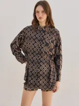 Camisa de algodón con estampado geométrico de ondas en tonos marrón y negro, corte holgado, mangas largas y cuello clásico.