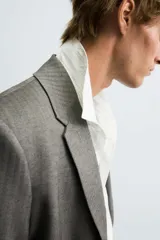 Blazer de corte boxy fit con estampado de espiga. Presenta cuello con solapas de muesca, cierre frontal de un botón, mangas largas con puños abotonados y bolsillos con solapa en la cadera.