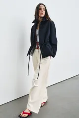 Parka de cuello alto con trabilla y manga larga, color azul marino. Presenta bolsillos laterales ocultos en la costura y cintura ajustable con cordón. El cierre frontal es con botones ocultos por solapa.