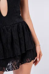 Vestido corto negro de encaje con escote halter, abertura en el pecho y falda de volantes.