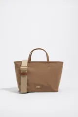 Bolso shopper mediano de mano Bimba y Lola color marrón, confeccionado en poliamida con detalles en cuero y herrajes metálicos dorados. Cuenta con doble asa de mano, correa de hombro ajustable de lona beige, cierre superior con cremallera y logo impreso en dorado al frente.