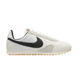 Championes Nike modelo Pre Montreal Racer Vintage, con diseño retro de perfil bajo. Presenta una base de tela técnica blanca con refuerzos de gamuza en tono gris claro en la puntera y el talón. Incluye el logo de Nike en color negro en los laterales y suela de goma con relieve para mayor tracción.