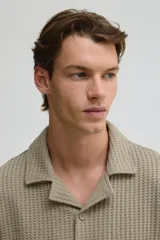 Camisa color caqui de manga corta con cuello resort y tapeta con botones. Tejido de punto waffle con corte holgado.