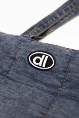 Bolso tipo shopper confeccionado en denim acolchado con diseño de paneles cuadrados. Presenta doble asa de hombro y un parche ovalado con el logo 'dl' en la parte frontal.
