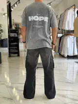 Remera oversize gris con efecto gastado, mangas cortas y estampa con texto blanco en el frente y en la espalda.
