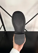 Botas negras de caña alta con suela track y tres hebillas decorativas en la parte trasera.