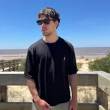 Remera negra tejida con cuello redondo y manga corta, con logo bordado en el pecho.