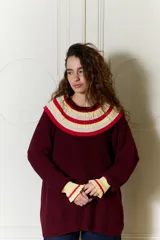 Buzo de punto bordó estilo oversize, con cuello babero amplio con volados y franjas en tonos amarillo y rojo, manga larga con terminación en volados.
