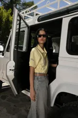 Remera tipo polo color amarillo pálido, de algodón, con cuello clásico y mangas cortas. Presenta un bordado de una rosa azul en el pecho.